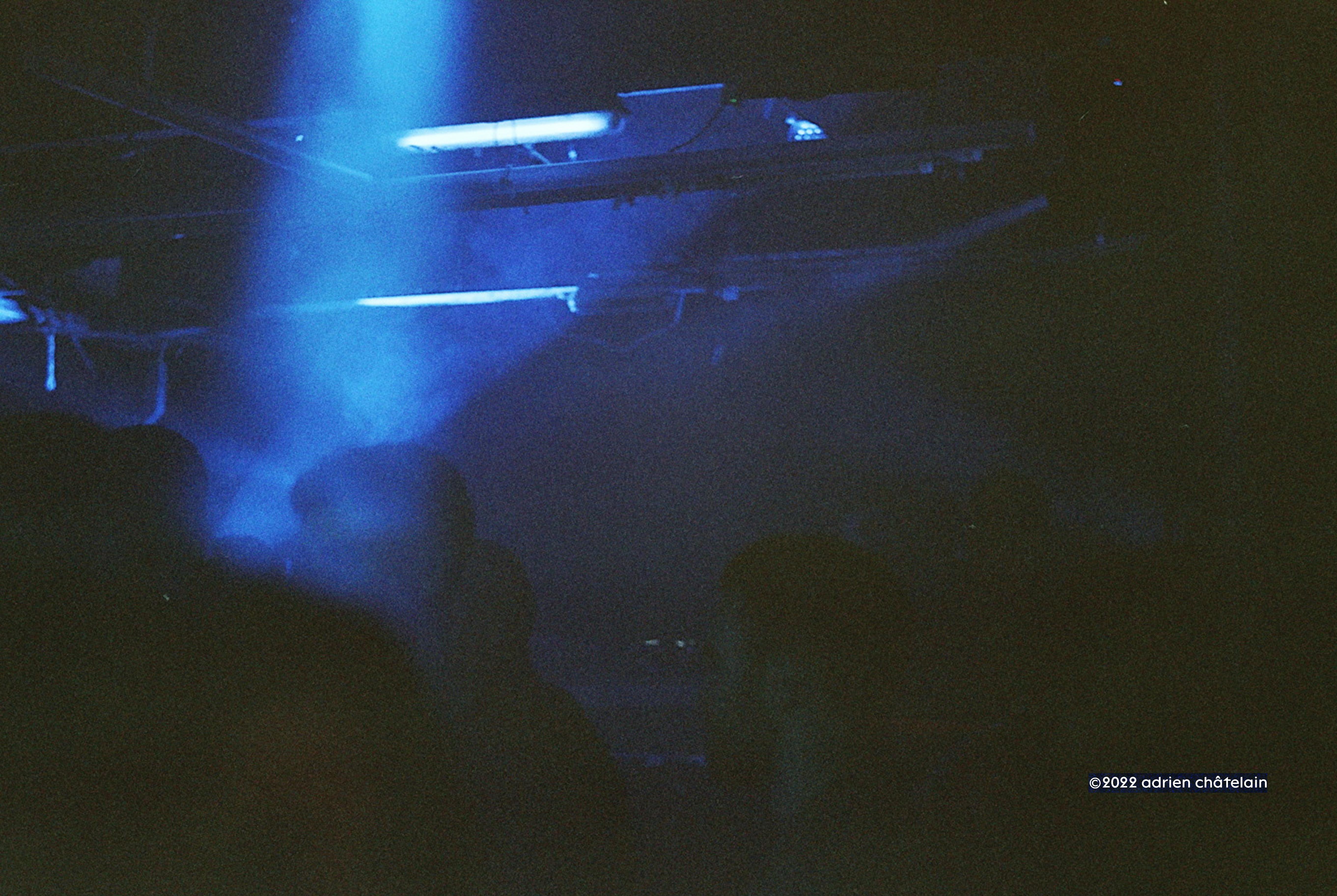 Patrons at a club in Manchester framed by a fogged beam of blue light